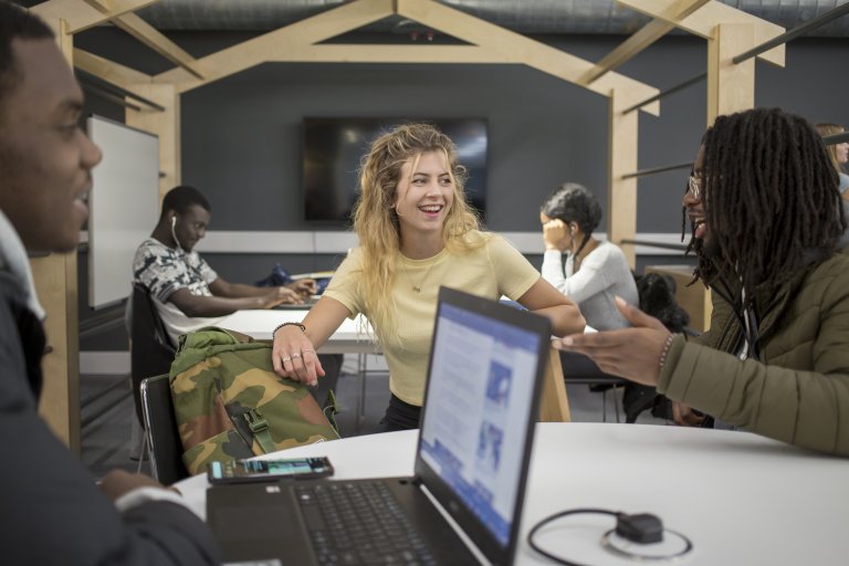 Group studying in informal study space with laptop in foreground